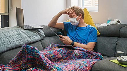 Man sitting in living room with mask and phone