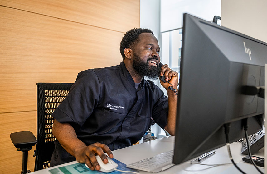 Man sitting at a computer while talking on the phone.