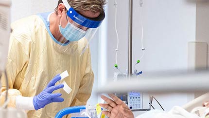 Caregiver attending to a patient in a hospital bed.