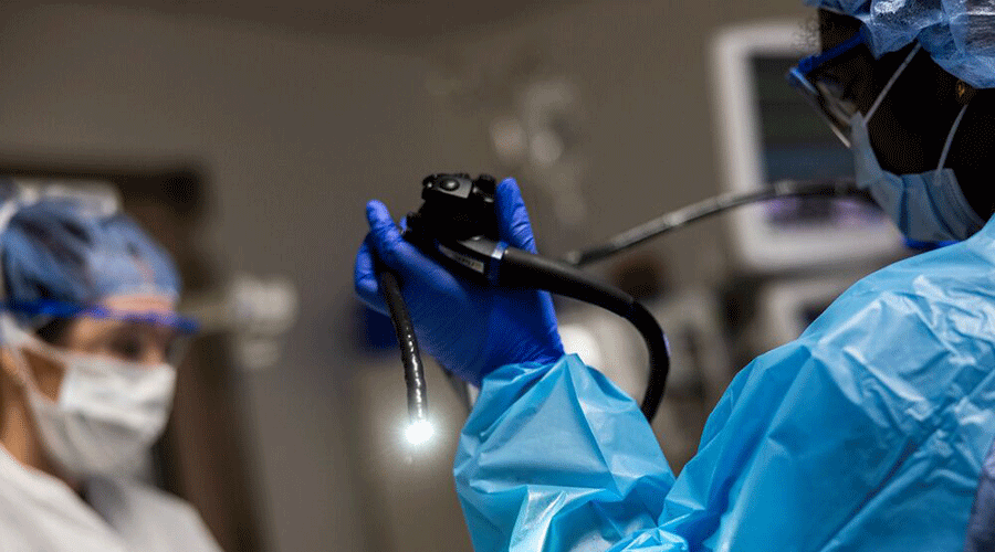 Medical staff in protective gear readies an endoscope for a procedure.