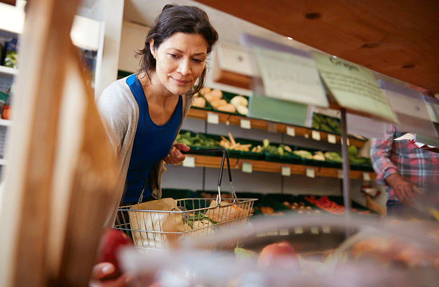 Person shopping for groceries and selecting fresh produce from a market.