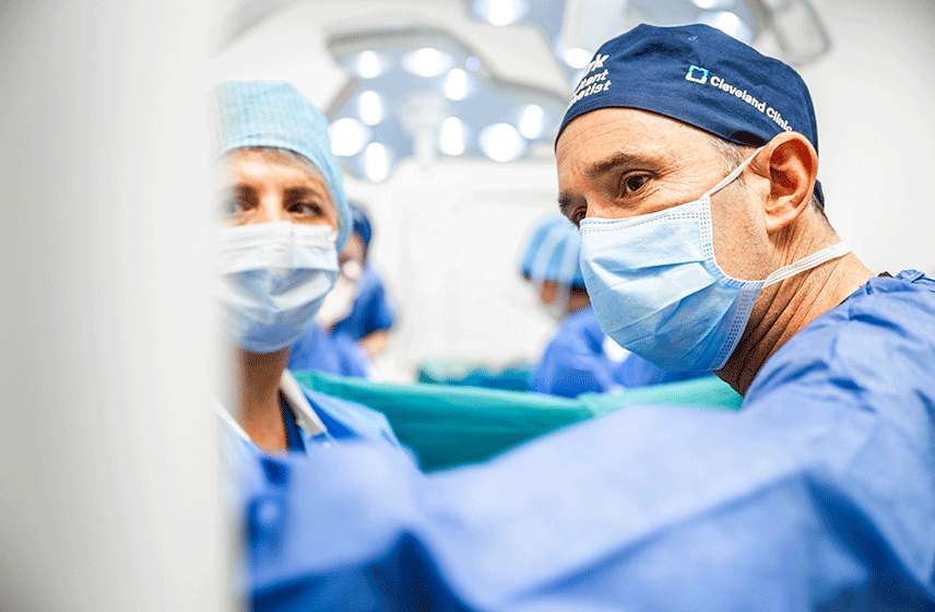 Surgical team in protective gear performing a procedure under high-intensity surgical lighting in an OR.