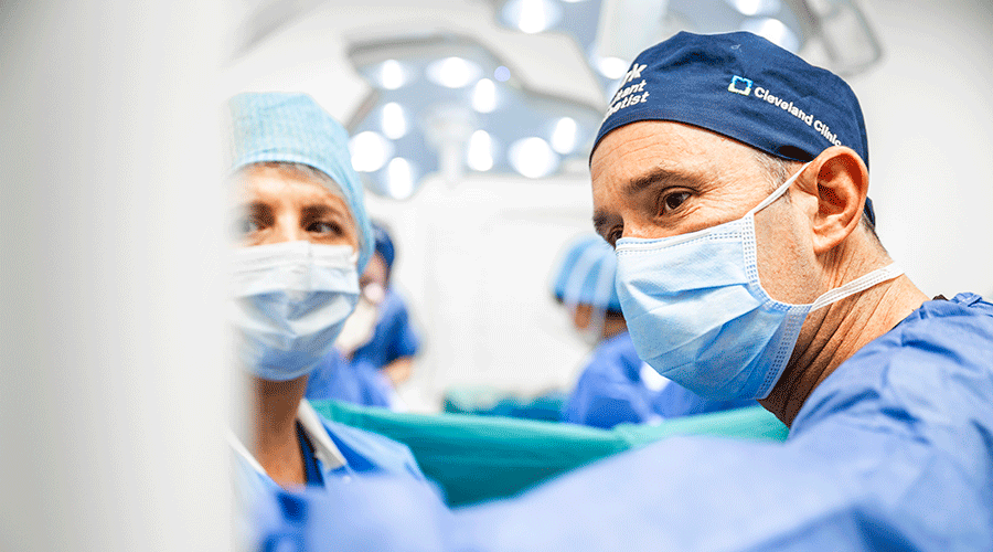 Surgical team in protective gear performing a procedure under high-intensity surgical lighting in an OR.