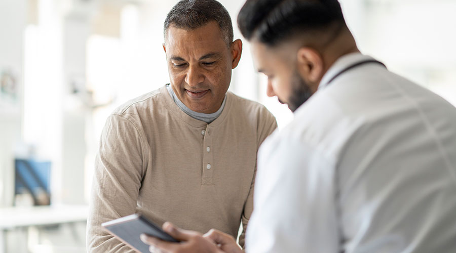 Consultant showing patient information on a digital tablet during a consultation.