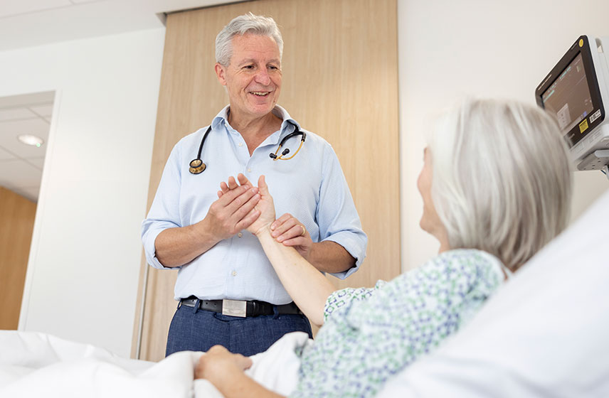 Consultant checking the pulse of a patient at her bedside.