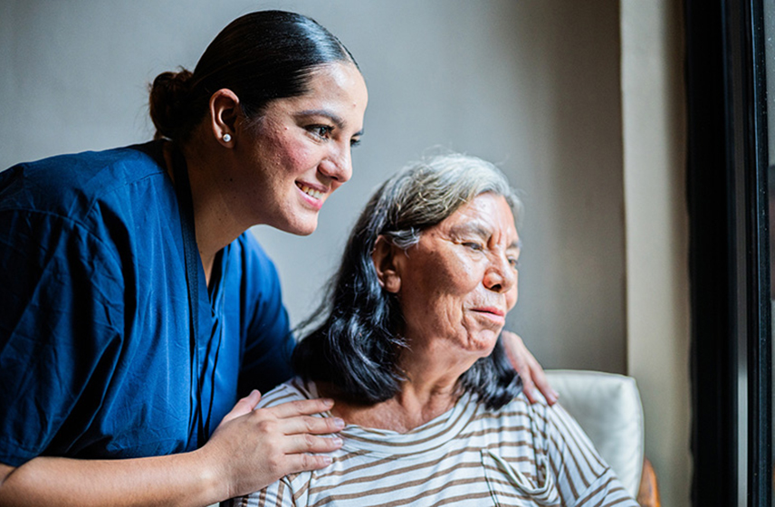 A caregiver with their hands on the shoulders of an older woman