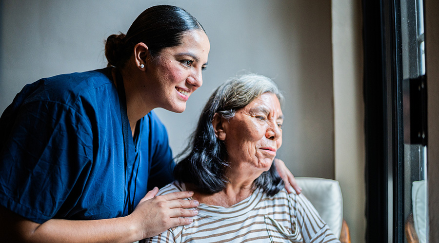 A caregiver with their hands on the shoulders of an older woman