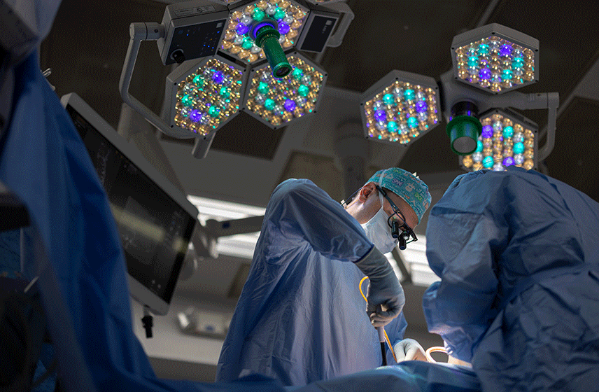 Surgical team performing an operation under bright multi-colored LED lights in an operating room.