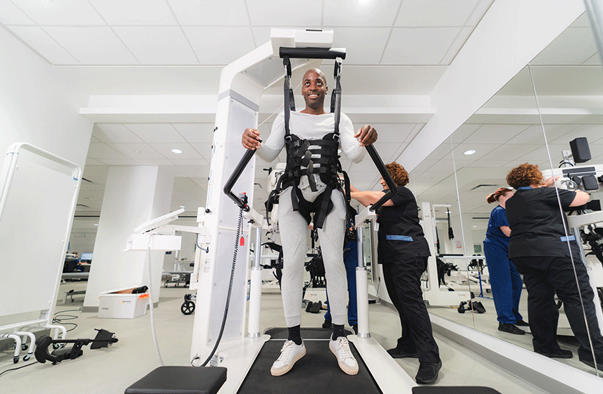 Patient receiving spinal cord rehabilitation in a well-equipped therapy room.