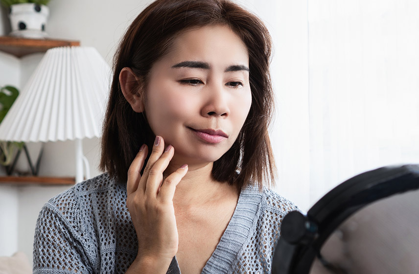 A woman with facial palsy looking at herself in a mirror.
