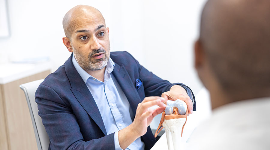 Doctor showing a patient an anatomy model of a hip and pelvis joint.