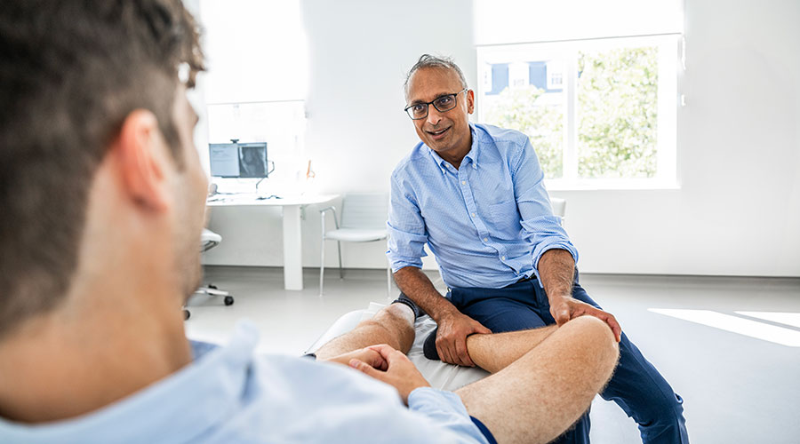 Health professional examining a patient's knee.