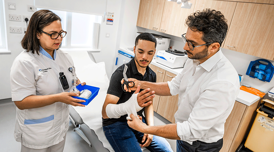 Doctor wrapping a patient's arm with a soft fabric bandage in preparation for a splint/cast.
