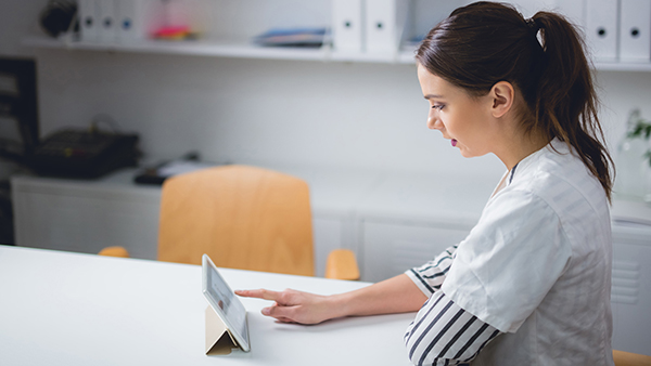 Woman sitting in break room talking to doctor on tablet