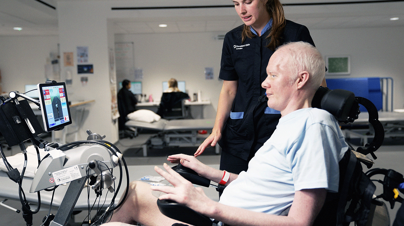 David Smith using a rehabilitation therapy bike while a Cleveland Clinic London physical therapist provides guidance.